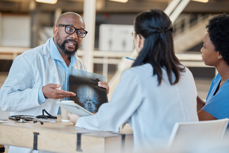 Black man, doctors and meeting with xray in clinic for test results, research or healthcare review